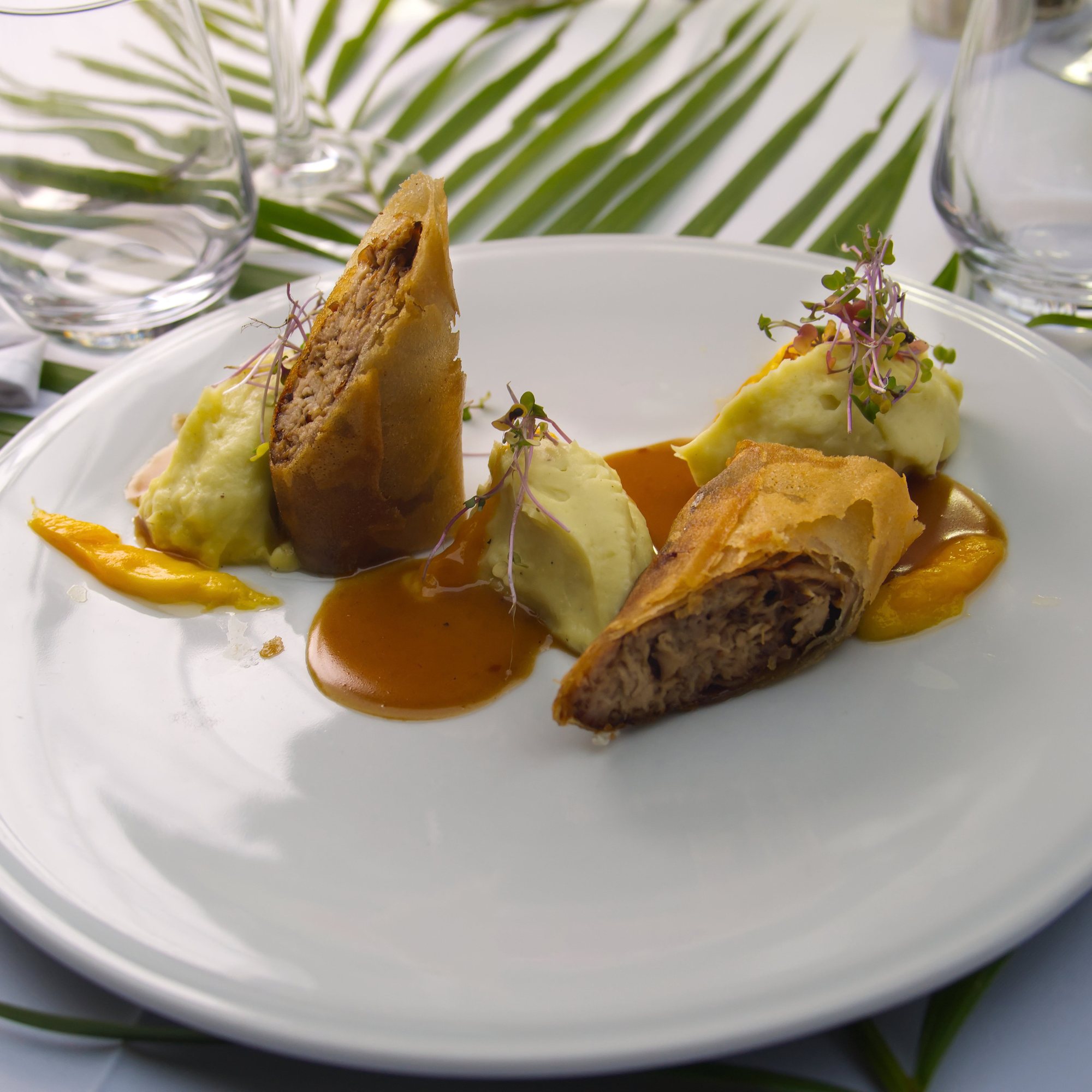 Une assiette de la Brigade, verres et feuilles de palmier sur la nappe