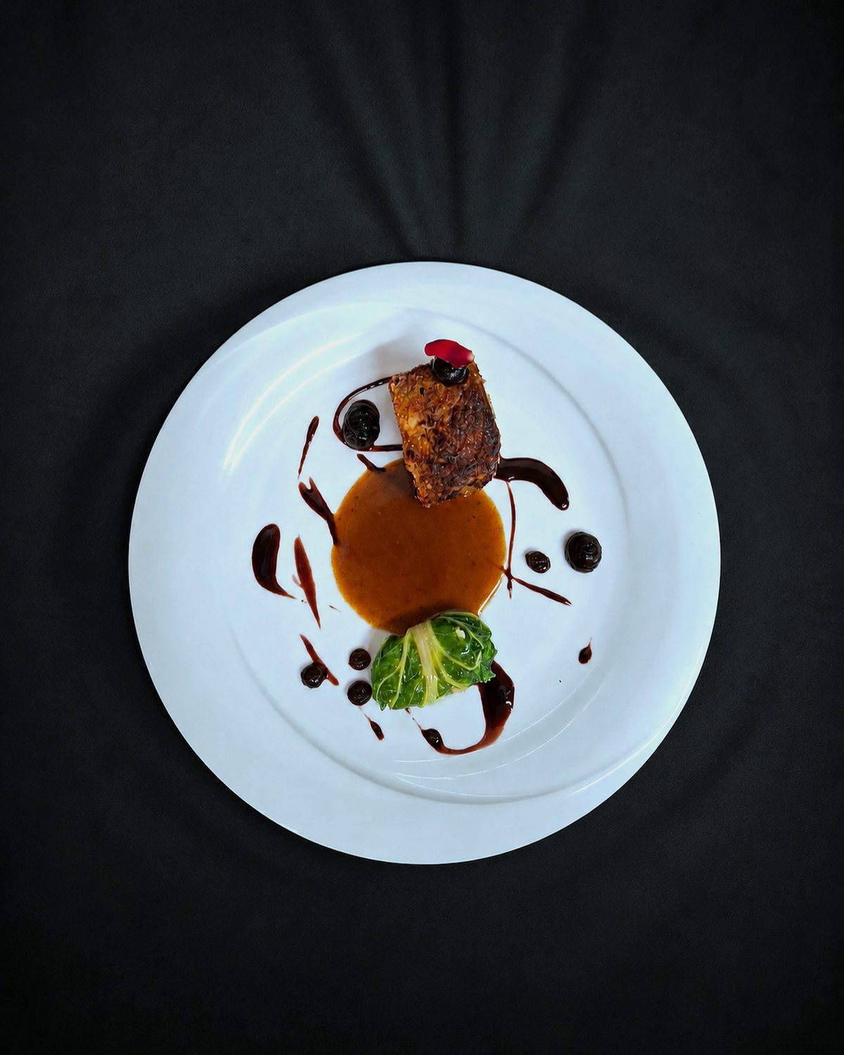 Une assiette dressée, vue du dessus, sur une nappe noire